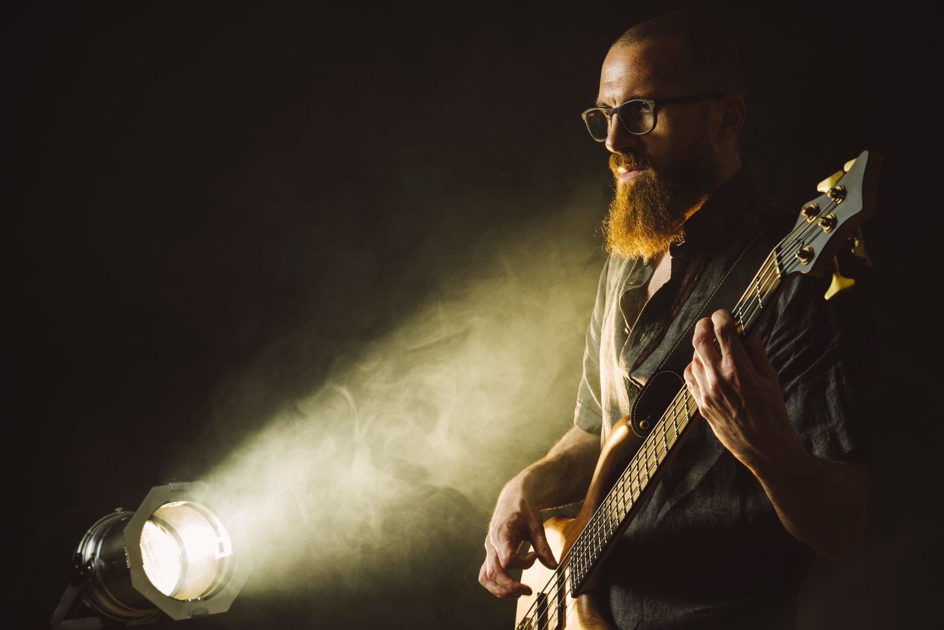 bearded-man-playing-bass-guitar-with-spotlight-e164820269141